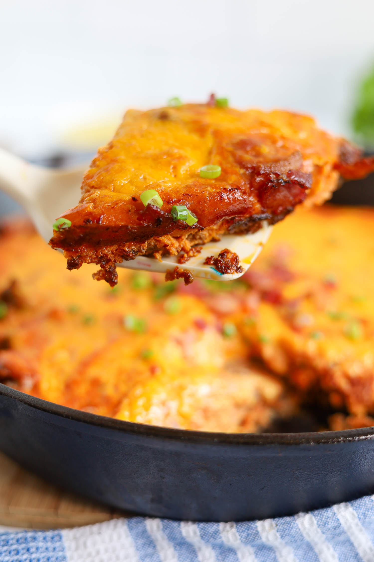 cutting up a slice of burger casserole with crispy cheese edges