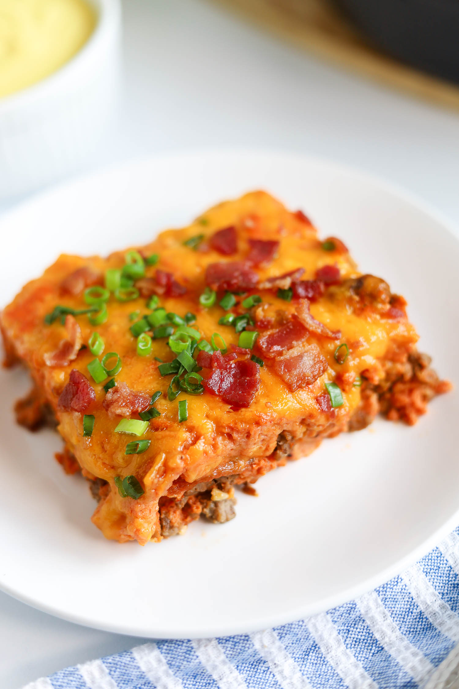 close up of cheeseburger casserole topped with bacon bits and green onions