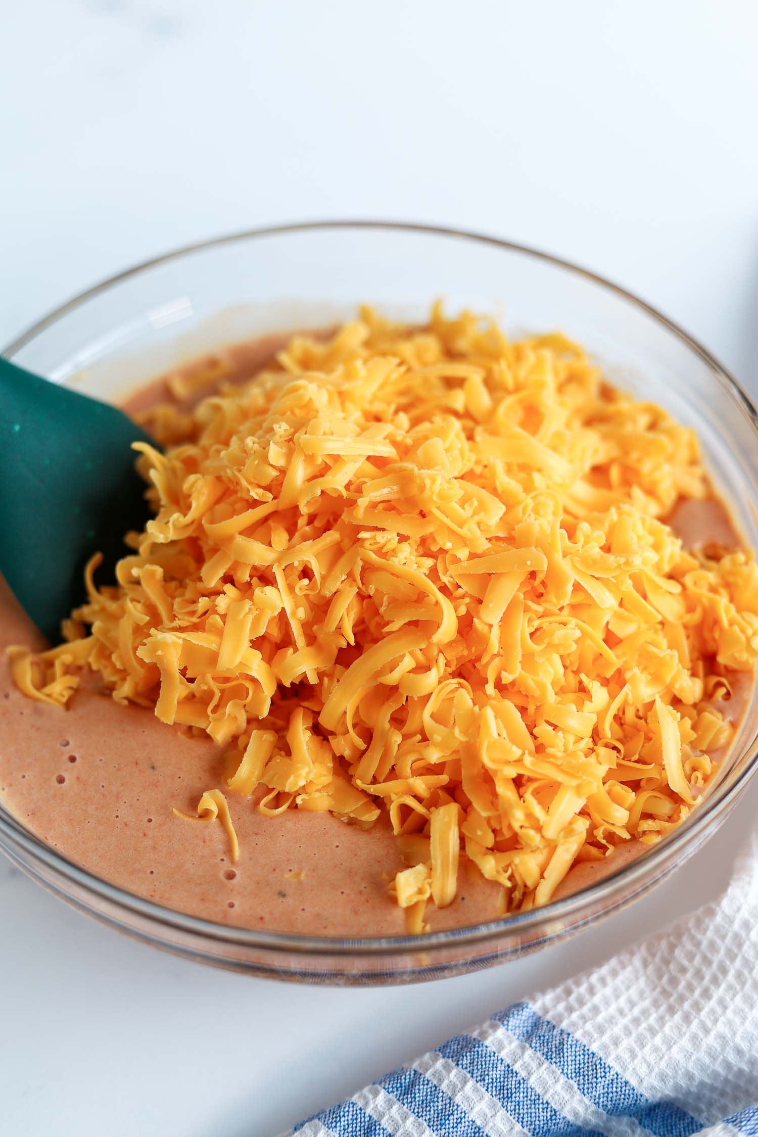 adding cheese to egg mixtures in a glass bowl