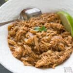 salsa verde chicken in white serving bowl with lime slice