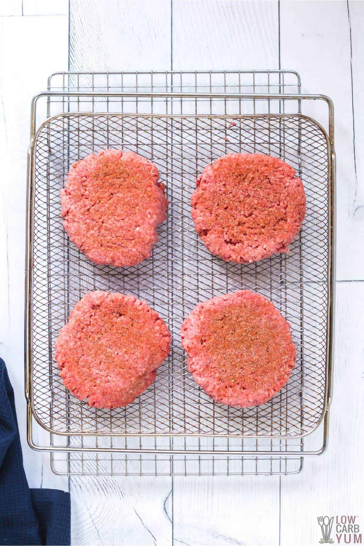 seasoned ground beef patties on air fryer basket