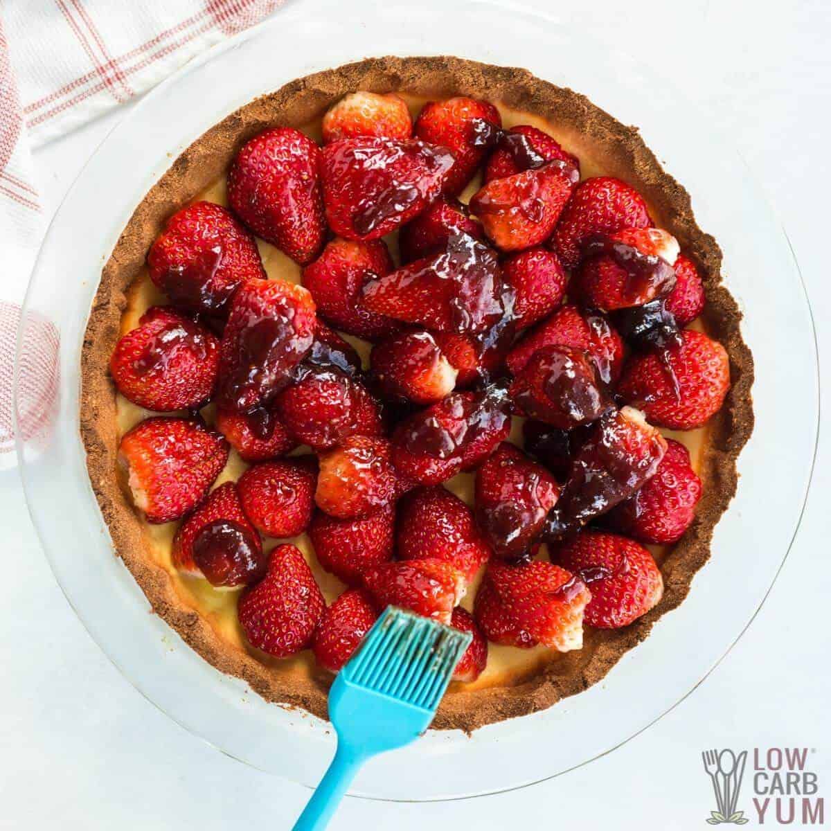adding strawberry jam glaze to cheese pie