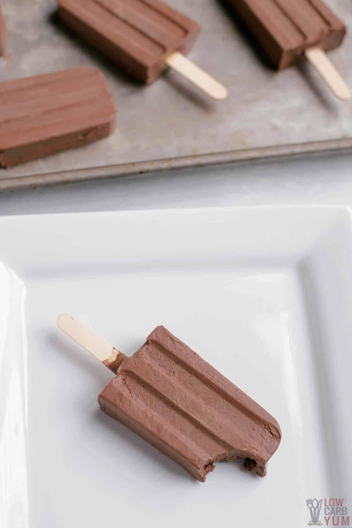 fudge pops on baking sheet and one bitten on white plate.