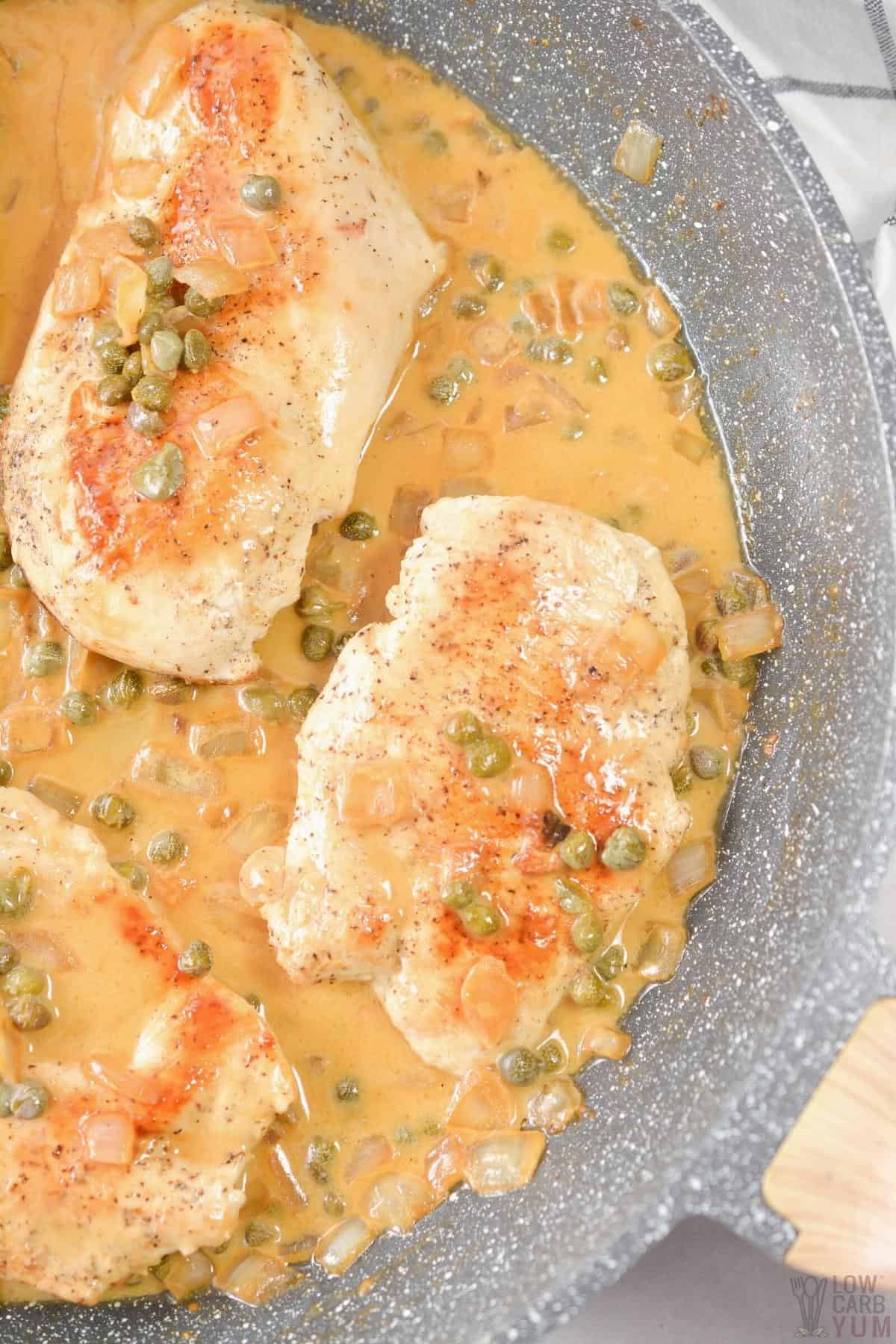 chicken breasts with lemon caper sauce in skillet.
