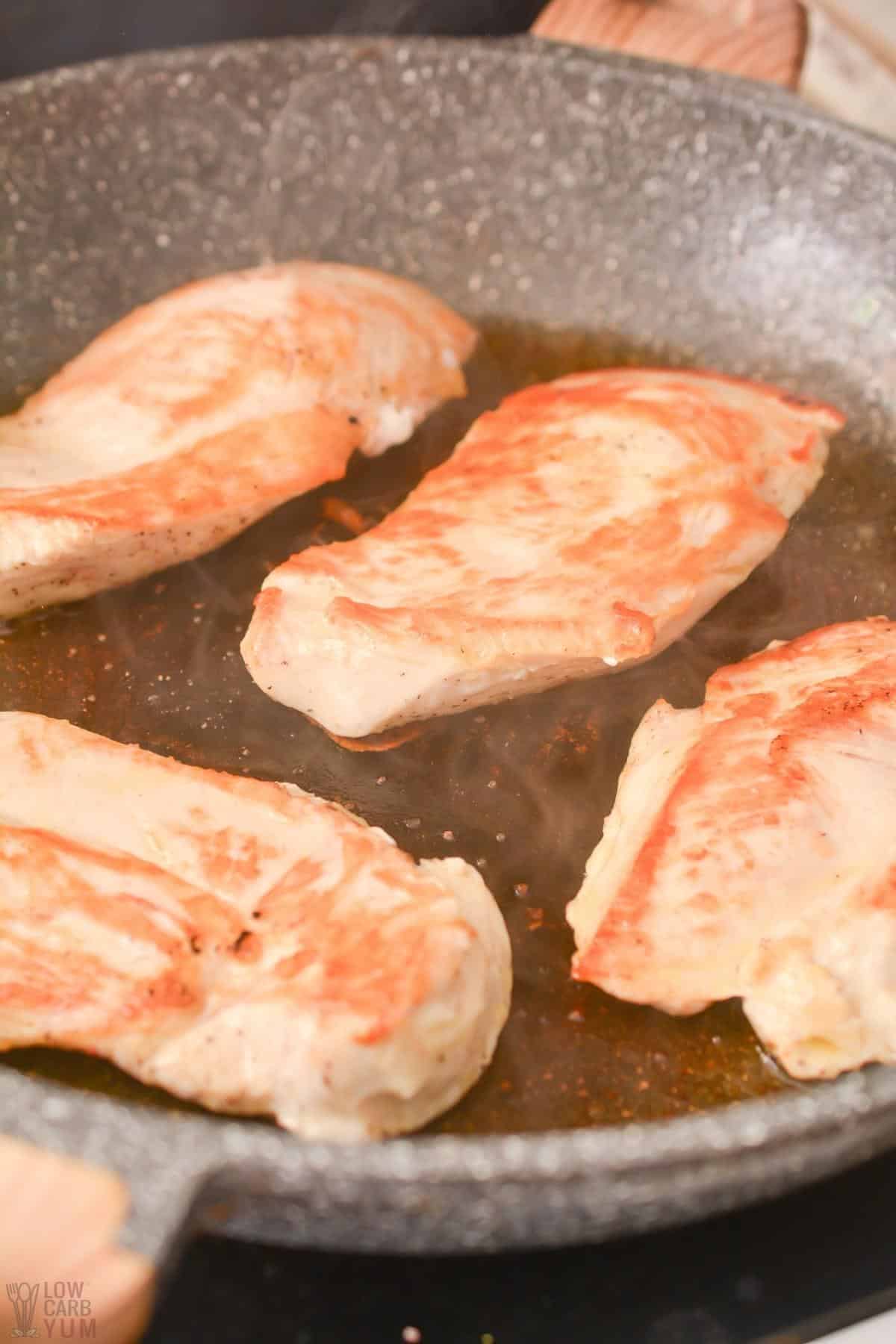 cooking chicken breasts in skillet.