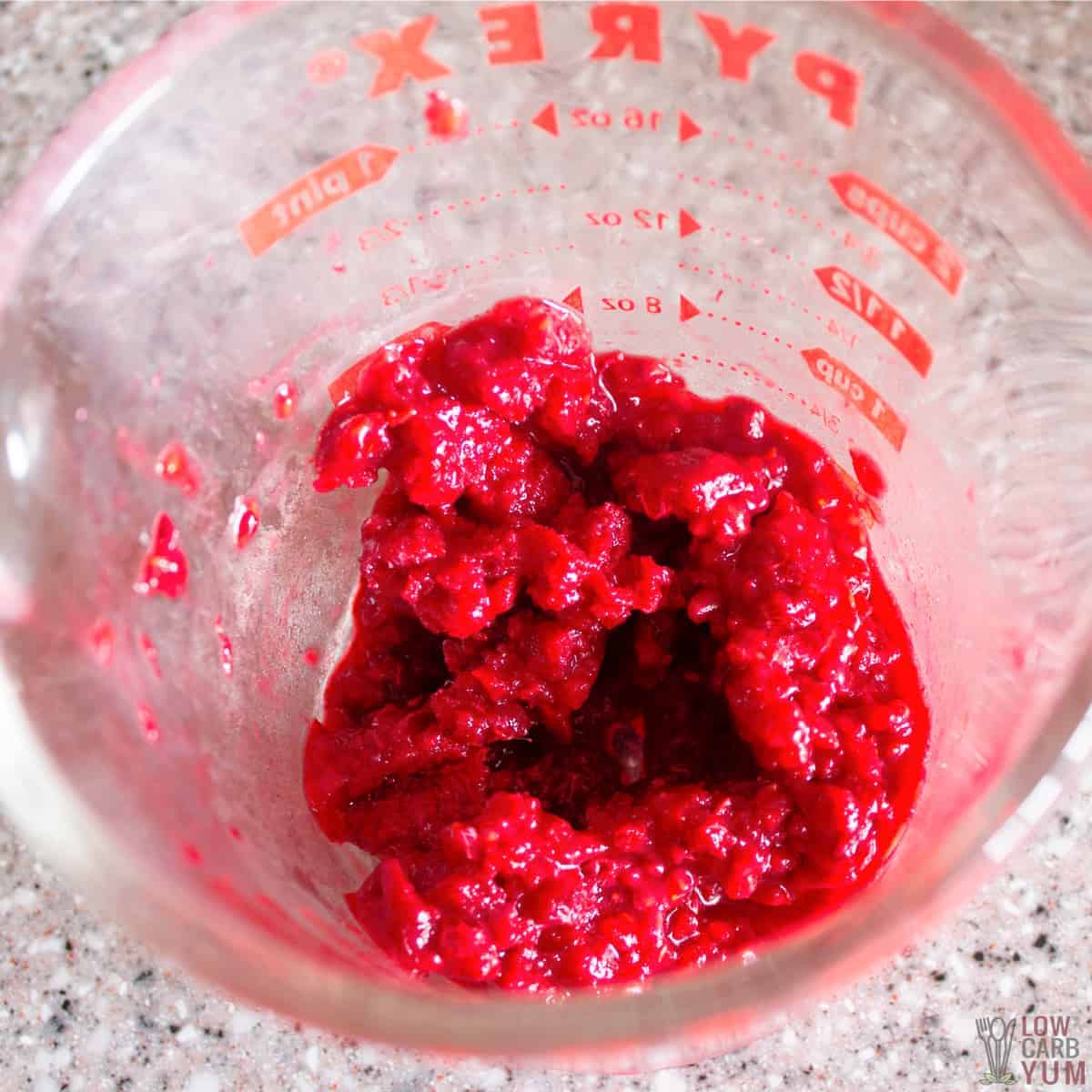 raspberry mash in glass measuring cup.