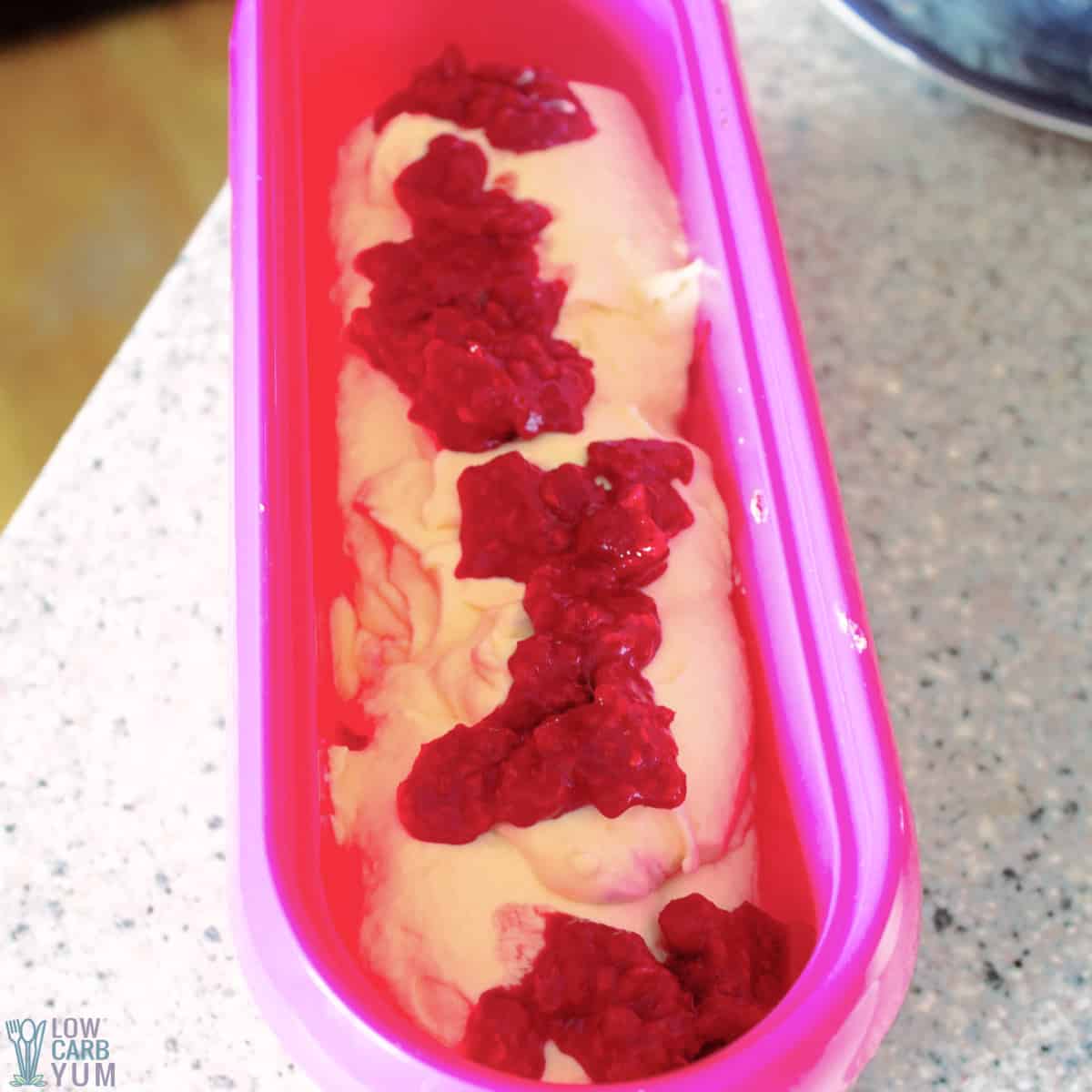 adding raspberry mash to churned soft ice cream.