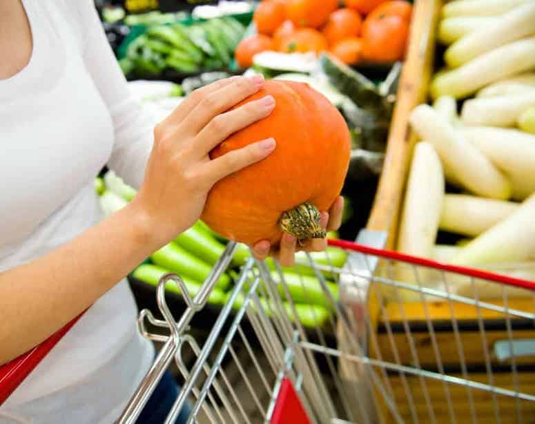 holding sugar pumpkin in produce aisle.