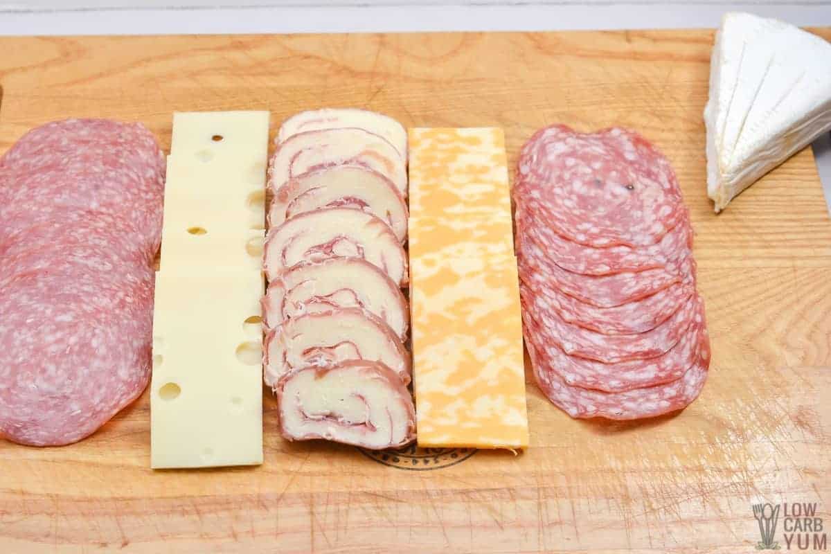arranging meat and cheese on board.