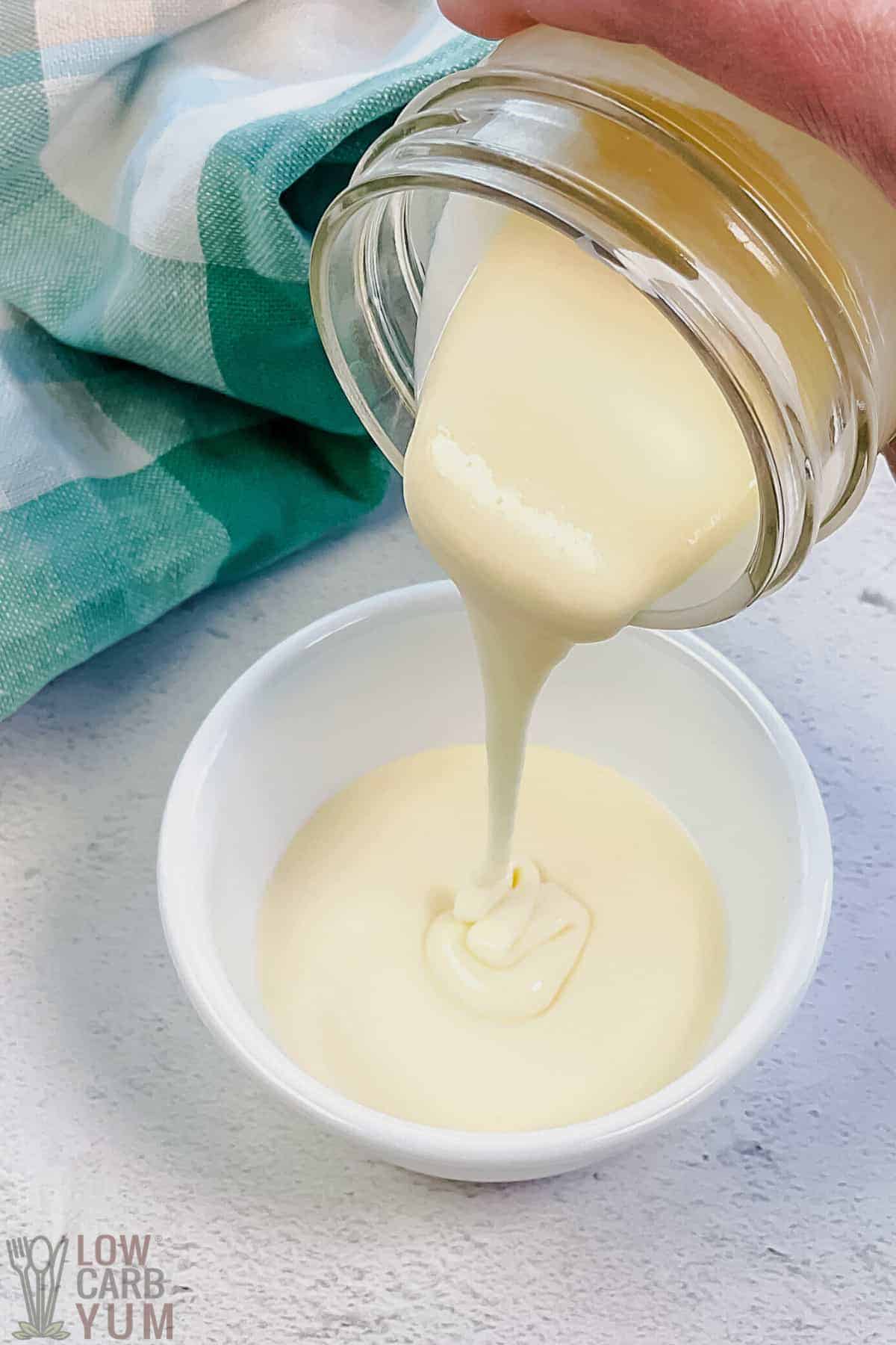 pouring sweetened condensed milk into small white bowl from jar.