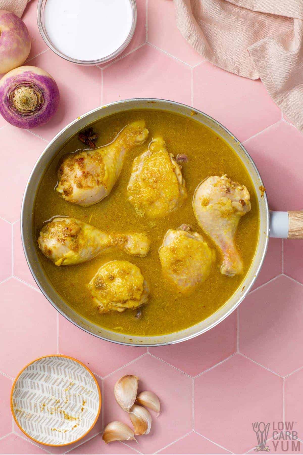 water added to chicken curry in pan.