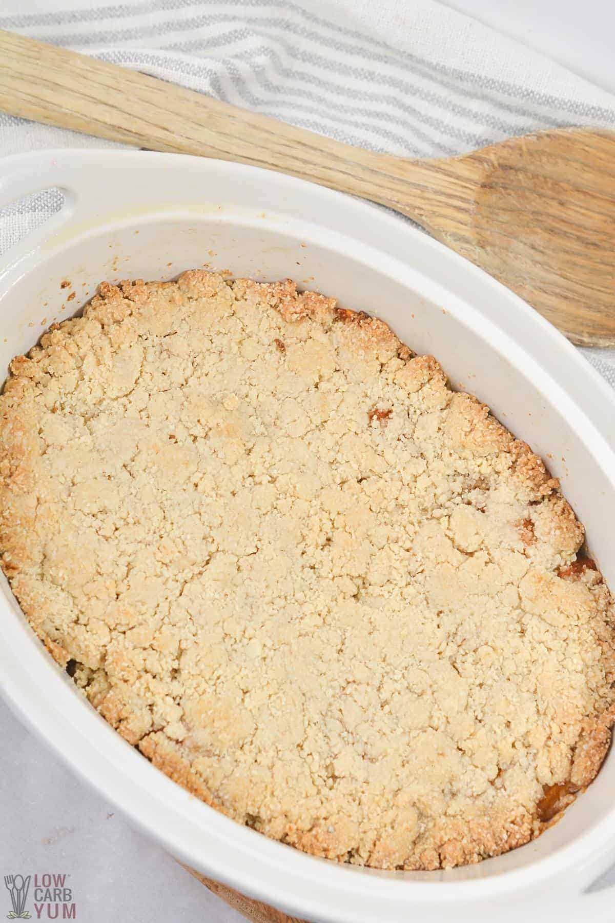 baked low-carb peach cobber in white oval baking dish.