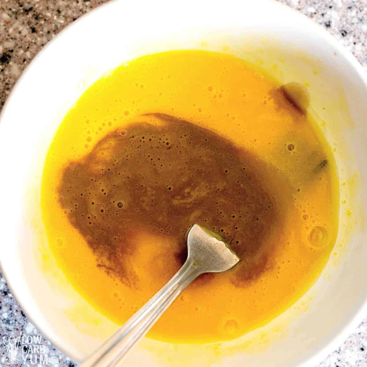 adding cocoa mixture to beaten egg yolks in white bowl.