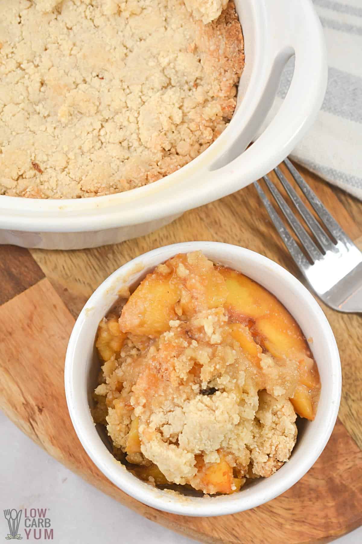 serving keto peach cobbler in small white bowl.