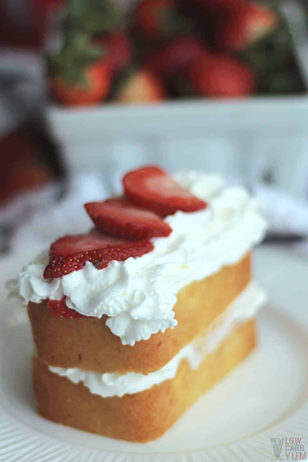 keto strawberry shortcake on white plate with strawberries in back.