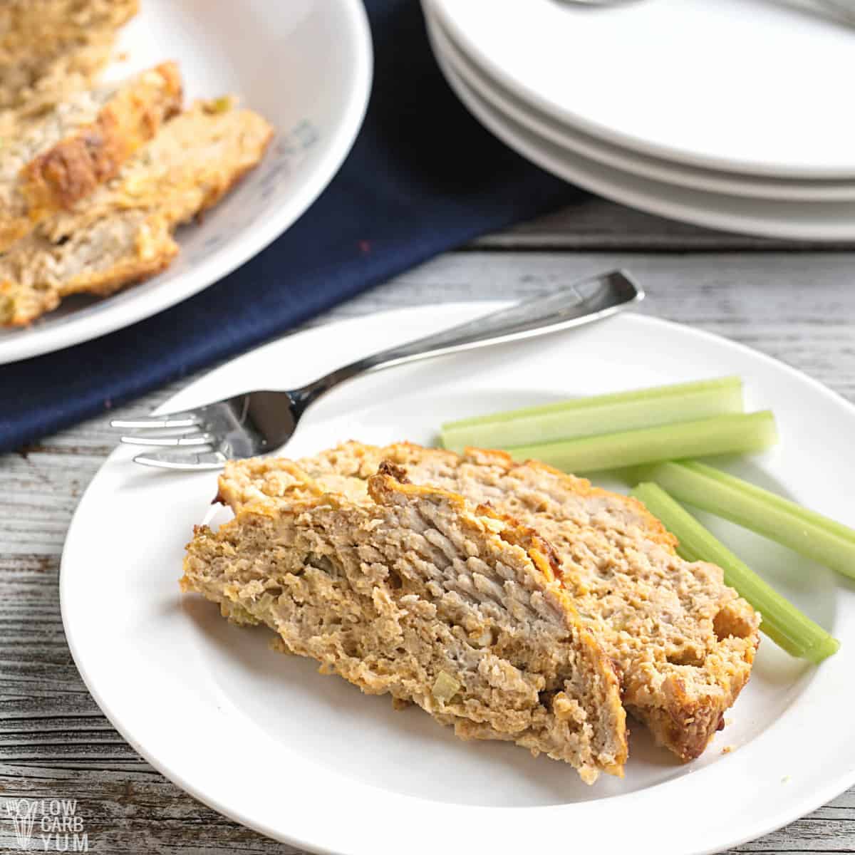 sliced chicken meatloaf on white plate with celery sticks.