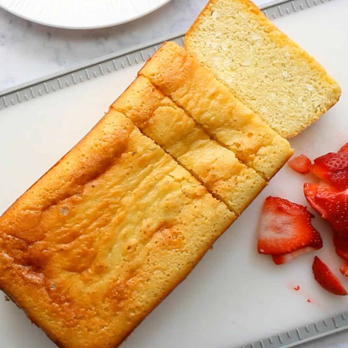 sliced poundcake on cutting board with sliced strawberries.