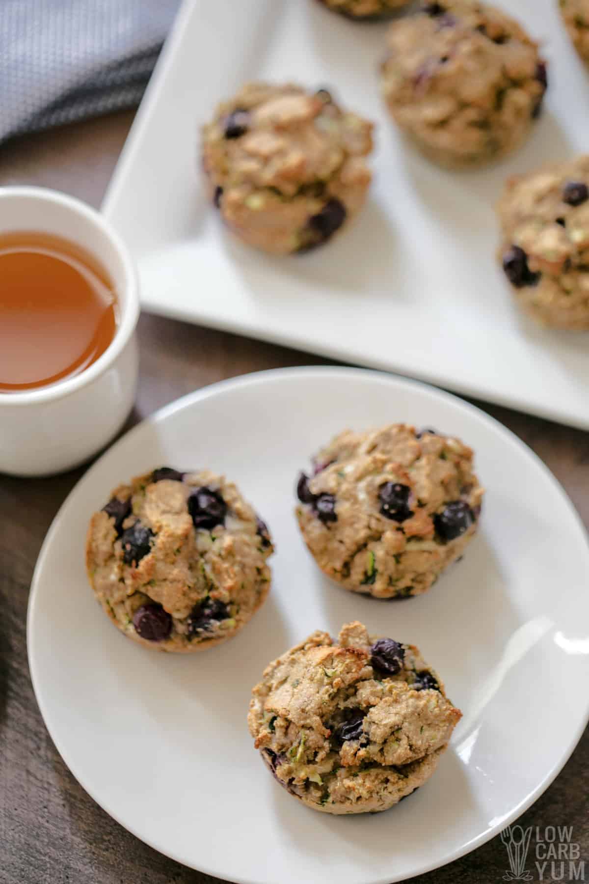 zucchini blueberry keto muffins on white plates.
