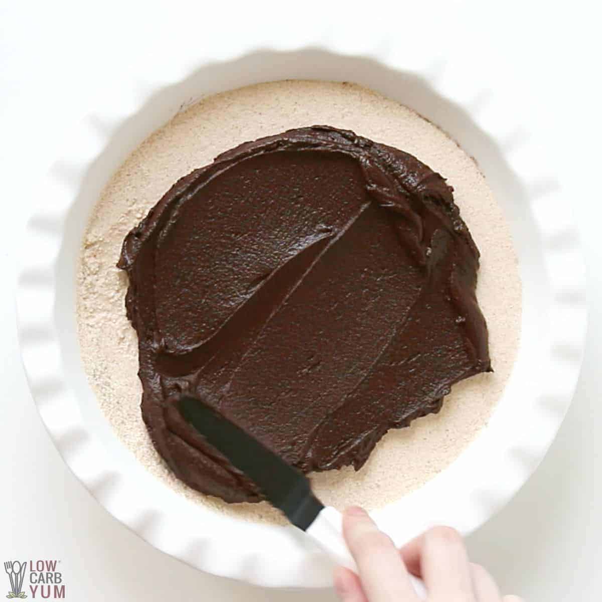 spreading chocolate ganache topping over peanut butter pie filling.
