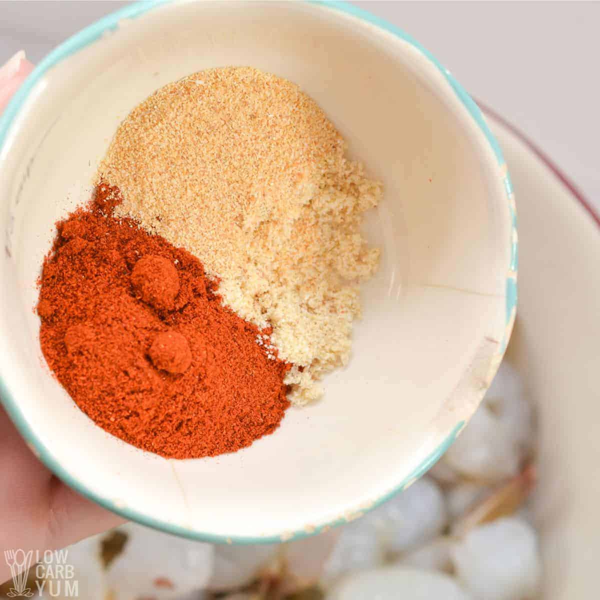 adding garlic powder and paprika to shrimp.