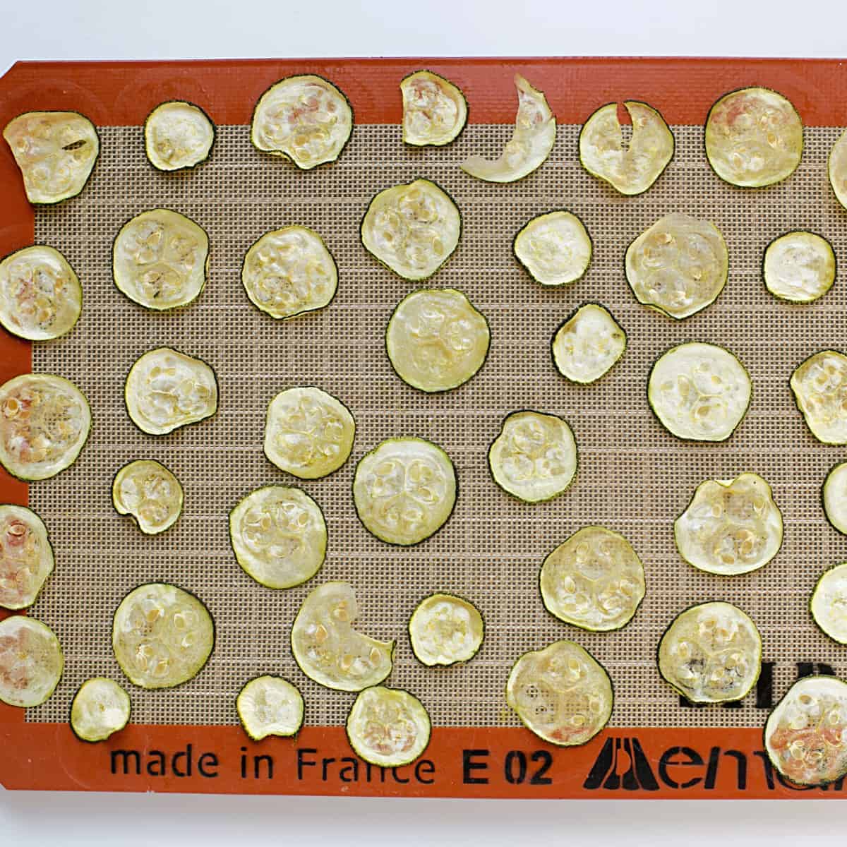 Gebackene Zucchinischeiben auf gefettetem Backblech.