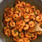 blackened shrimp with wooden spoon in skillet.