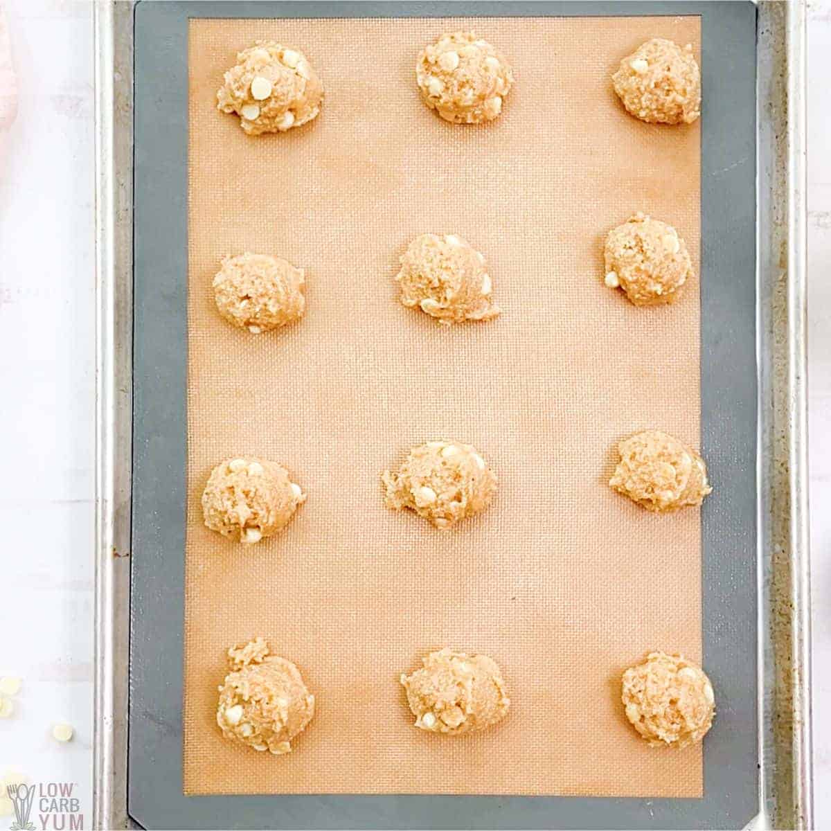 cookie dough scoops on lined baking sheet.