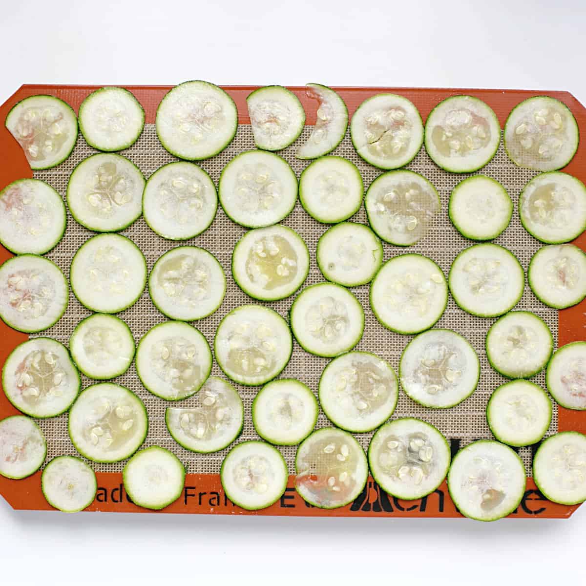unbaked zucchini slices on lined baking sheet.