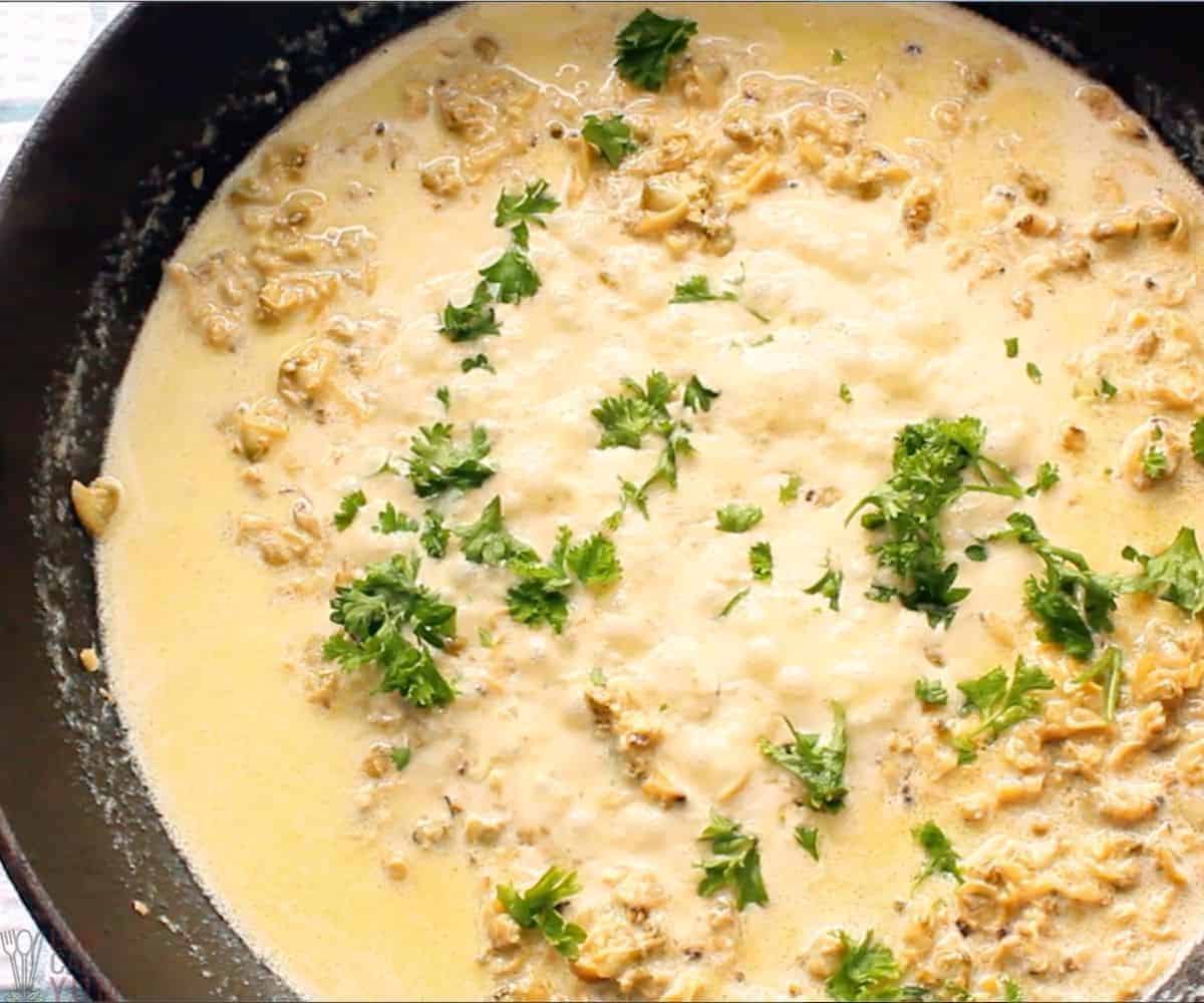 white clam sauce in skillet garnished with parsley.
