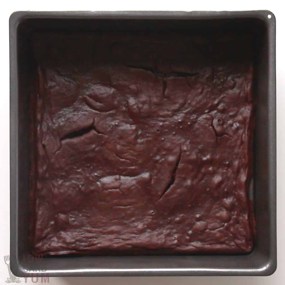 baked flourless brownie base in square baking pan .