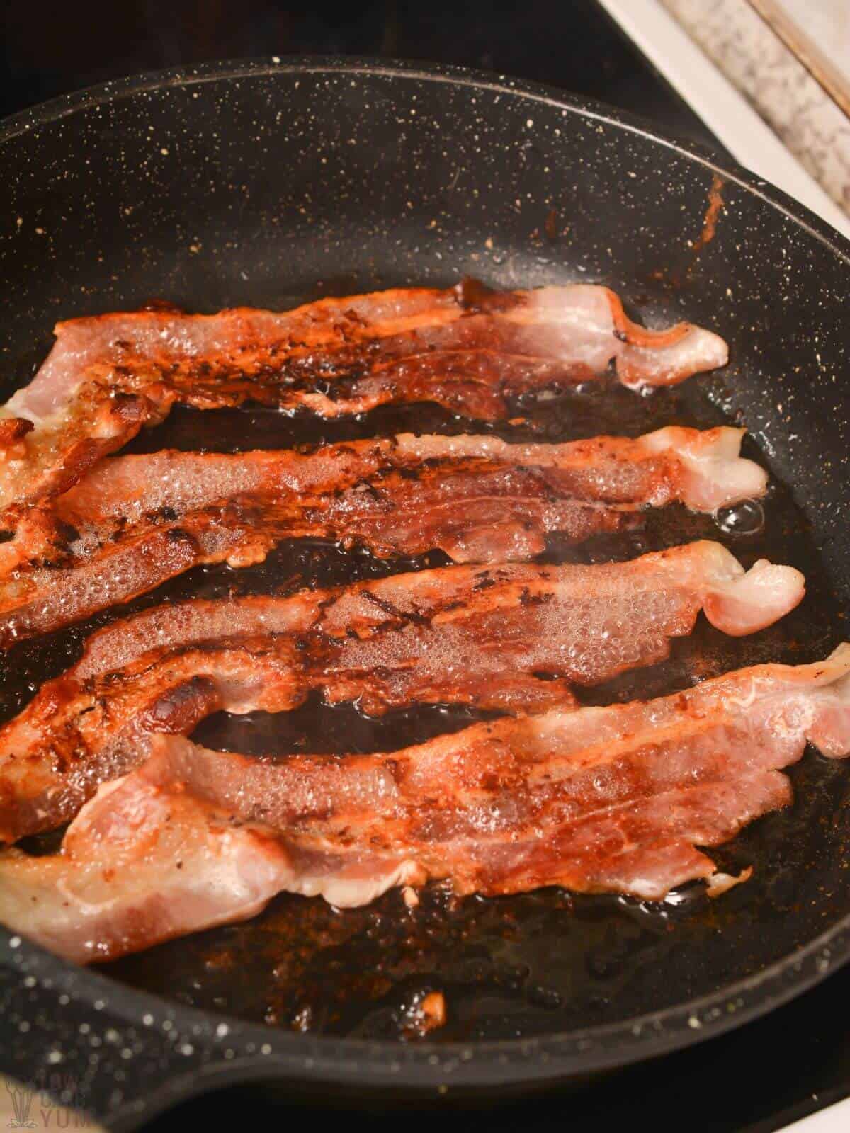 cooking bacon strips in skillet.
