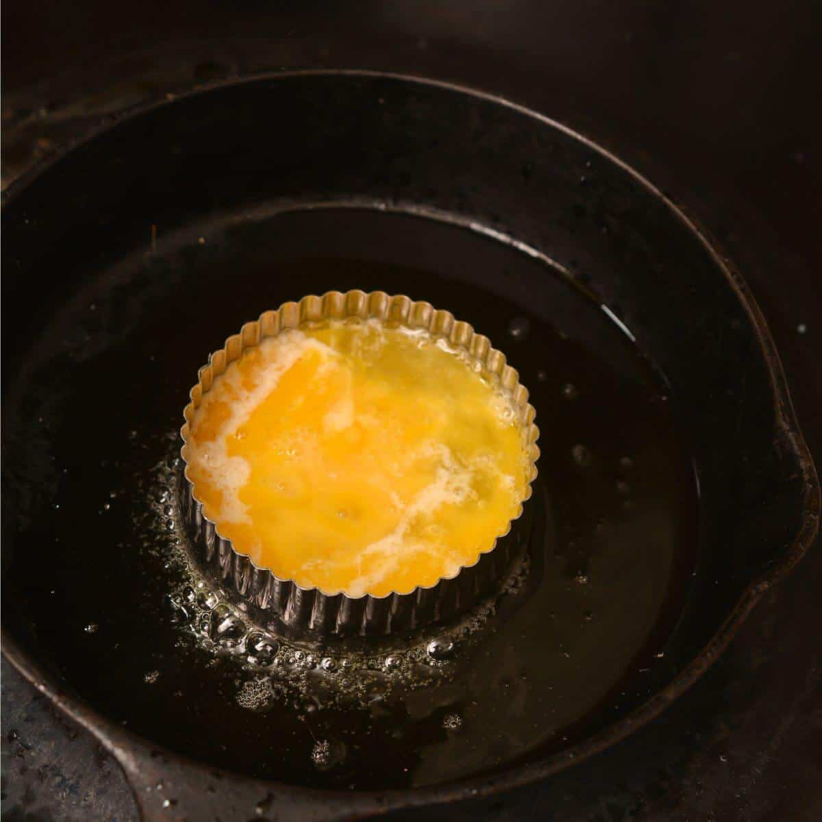 cooking egg in iron skillet.
