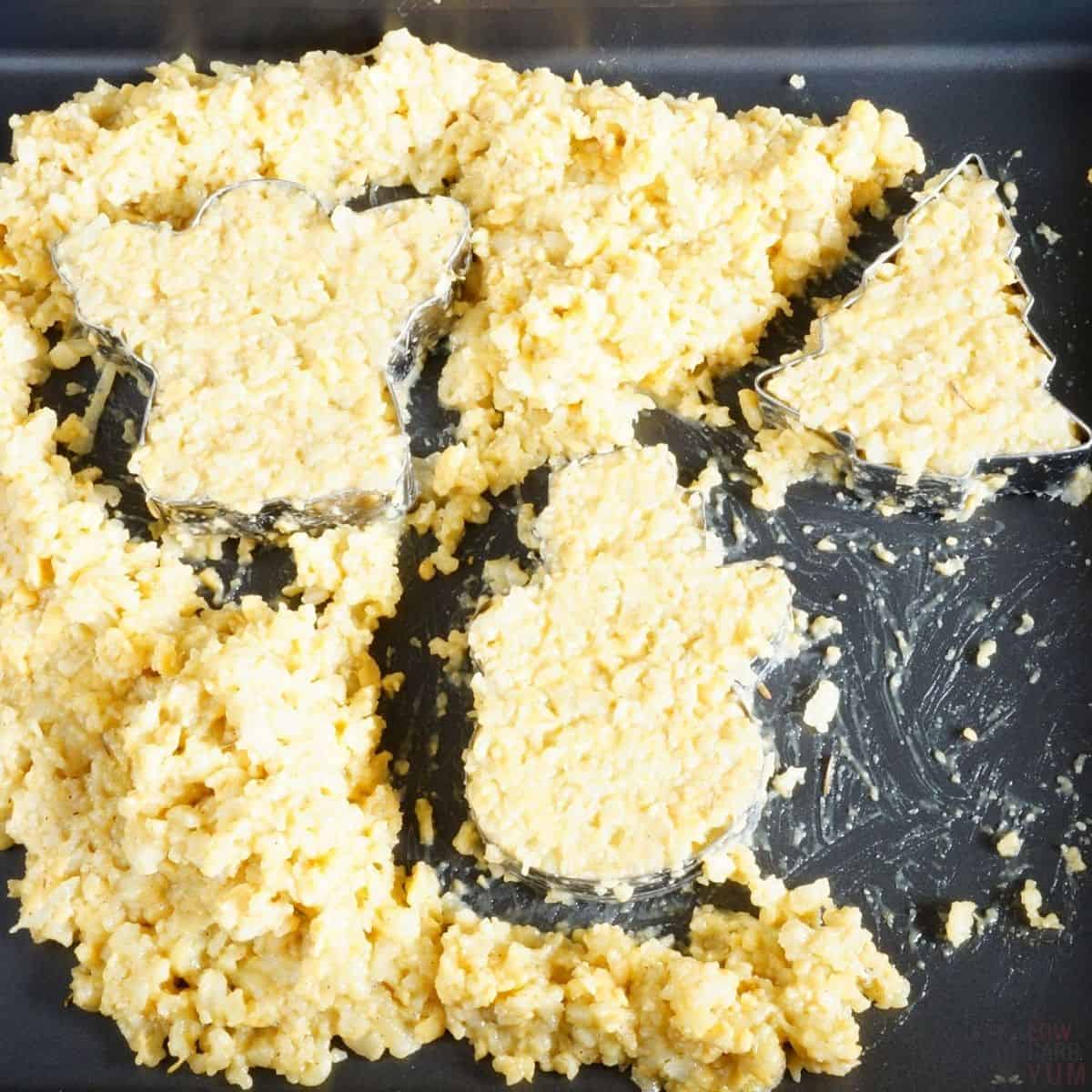 filling the cookie cutters with cauliflower mixture.