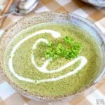 indian spinach soup in bowl with coconut cream garnish.