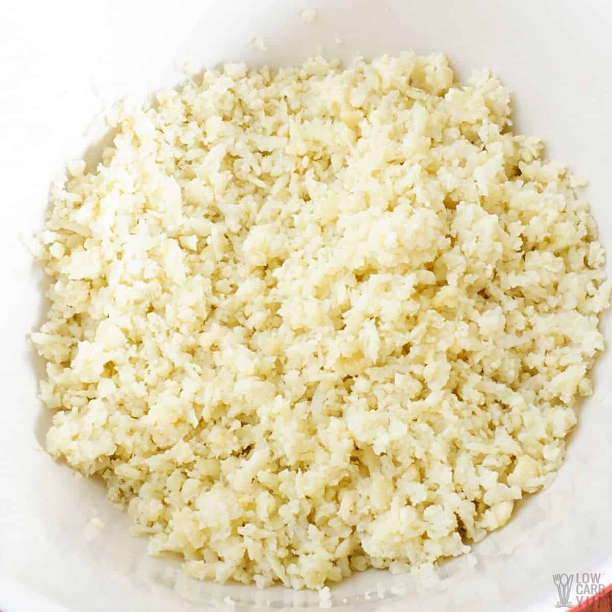strained cauliflower rice in white mixing bowl.
