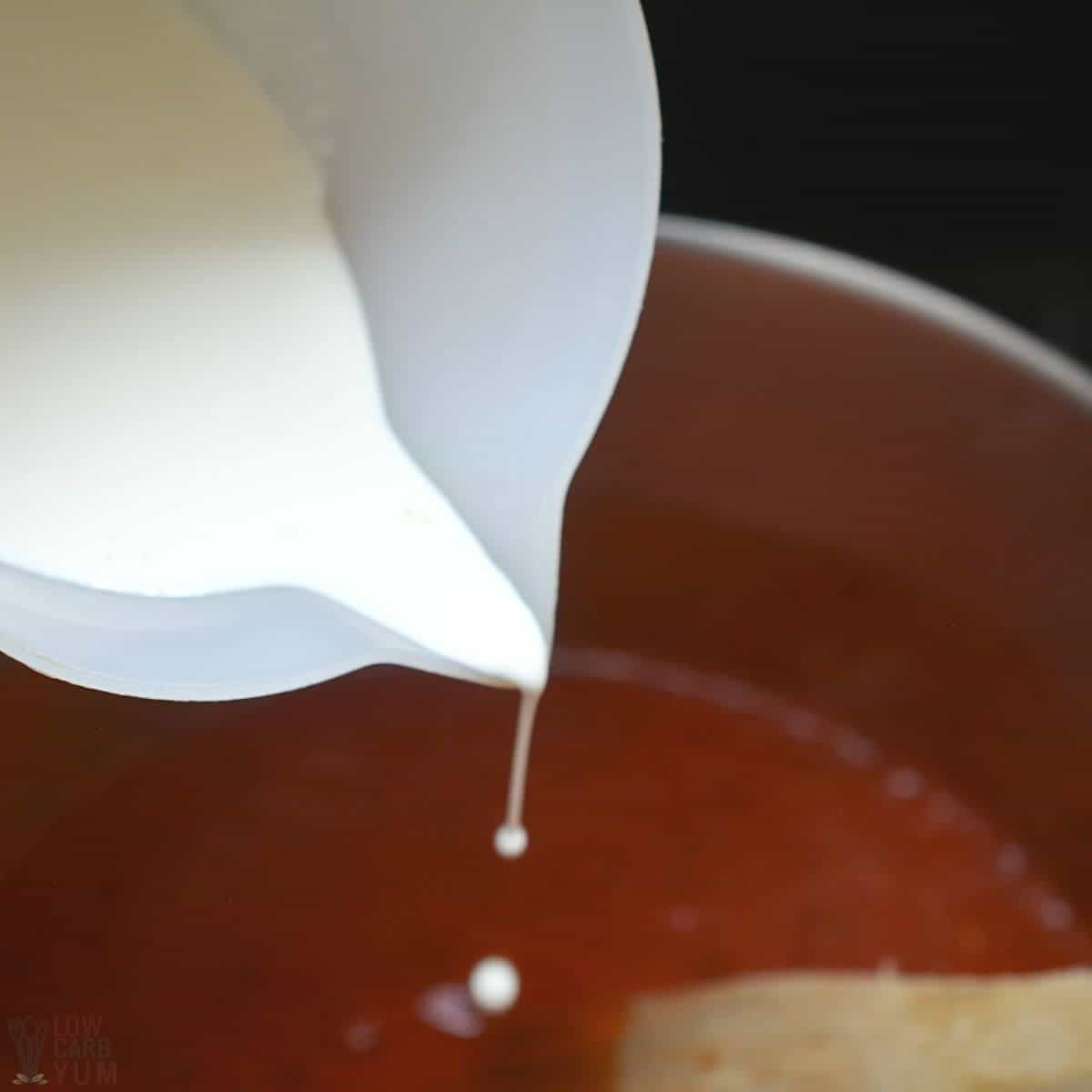 adding heavy whipping cream to soup in pot.