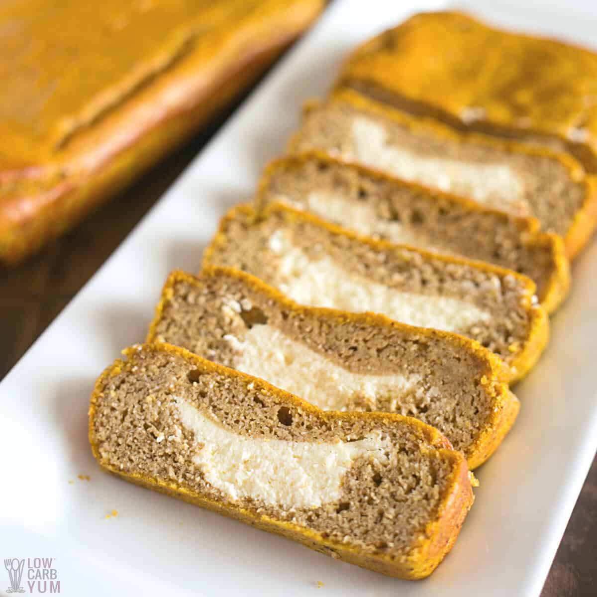 slices of cream cheese pumpkin bread on white platter with loaf.