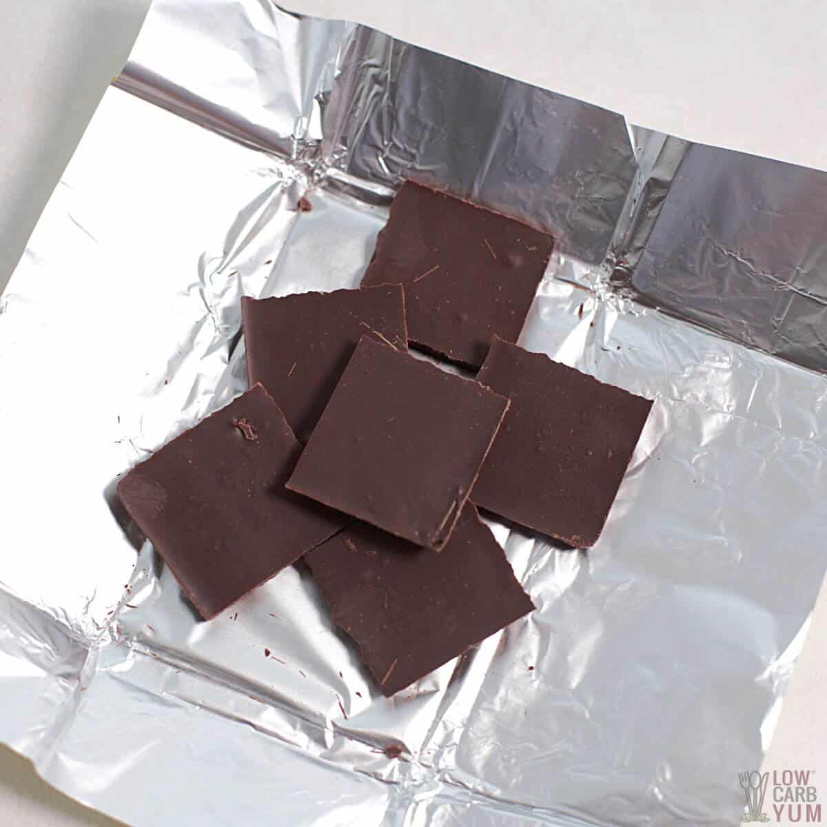 dunkle Schokoladenquadrate auf Folienverpackung.