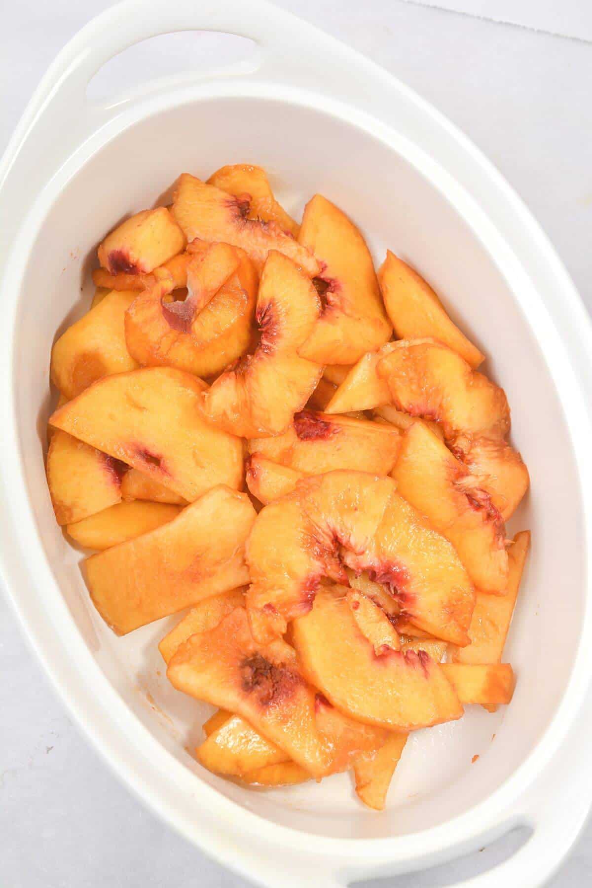 sliced and peeled peaches in baking dish.