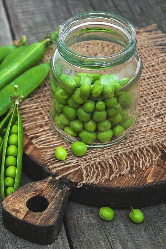 peas in jar on wood cutting board.