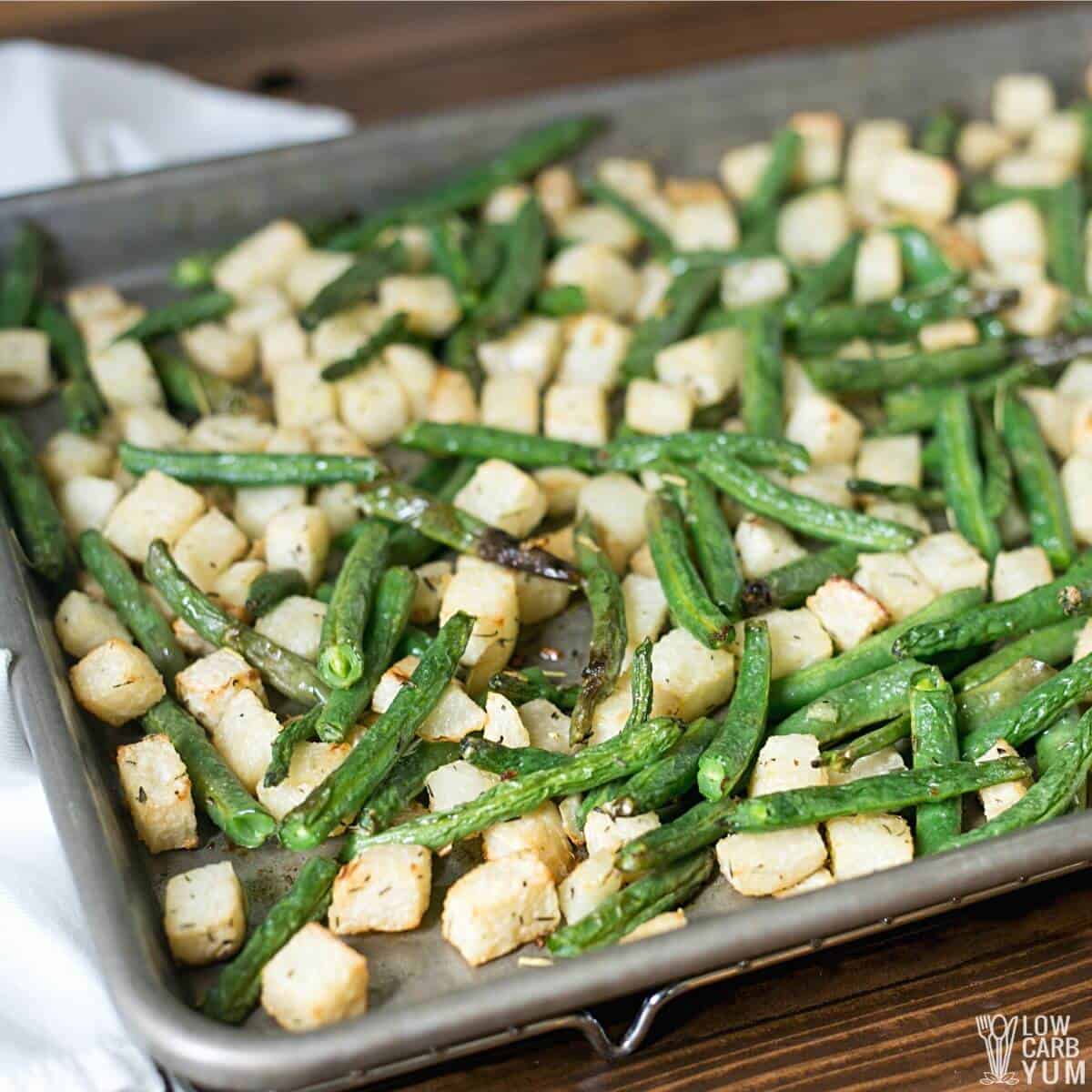 closeup of roasted jicama and green beans on baking sheet.