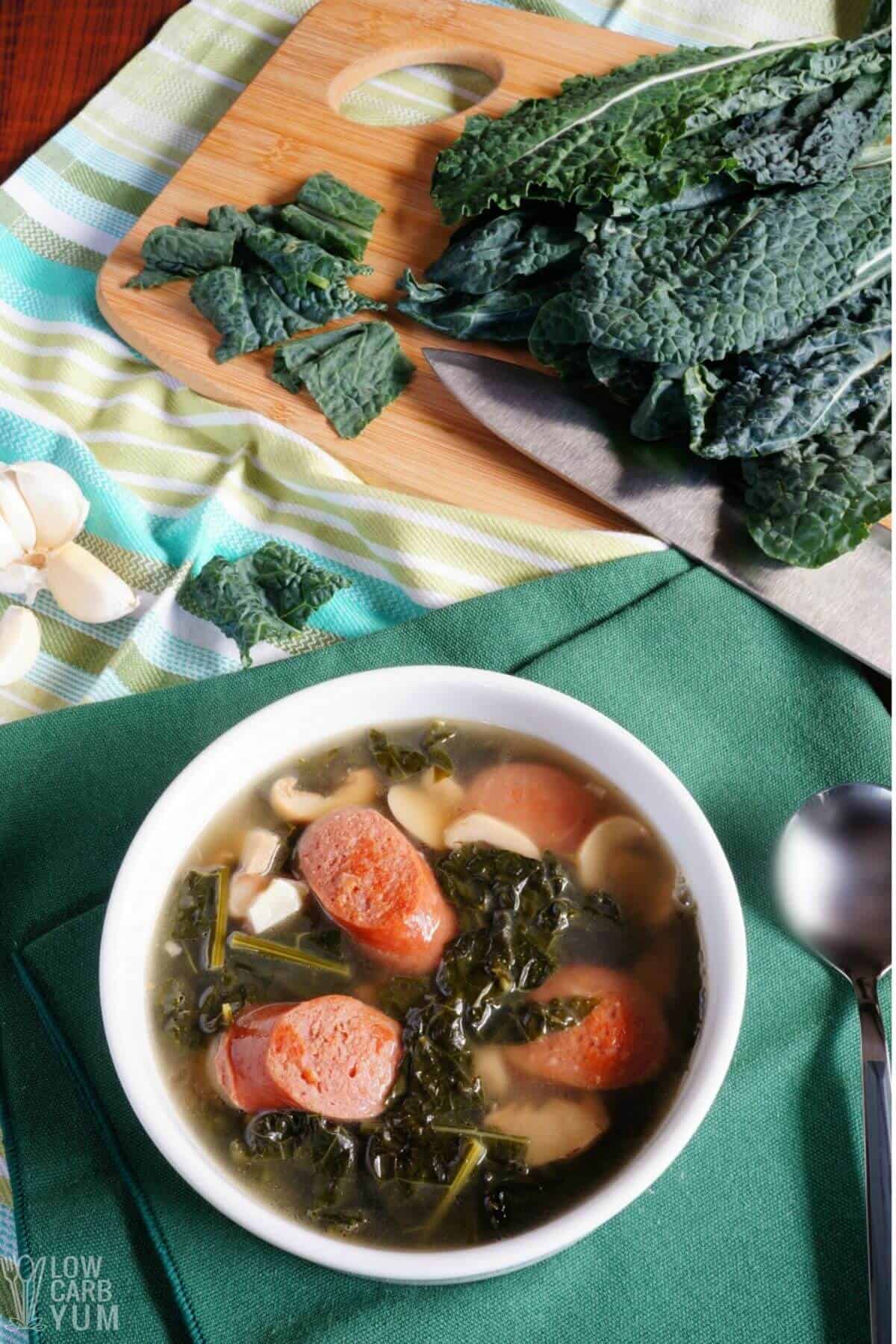 serving bowl of sausage kale soup with kale and garlic.