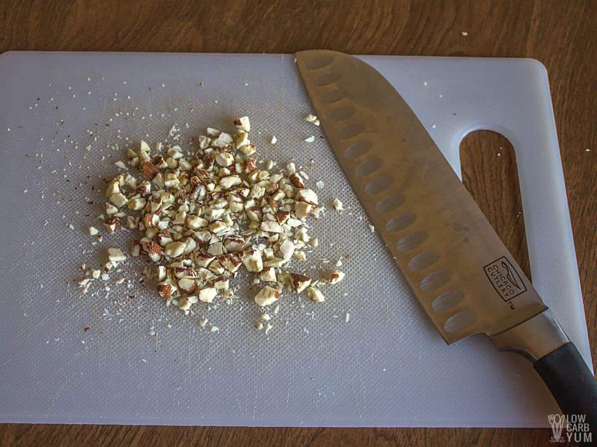 chopped almonds on white cutting board with knife.
