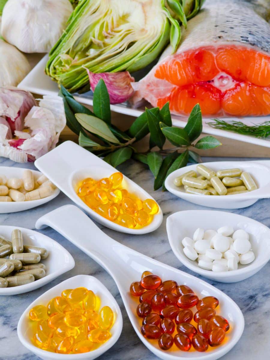 mini bowls of vitamin supplements with salmon and fresh veggies