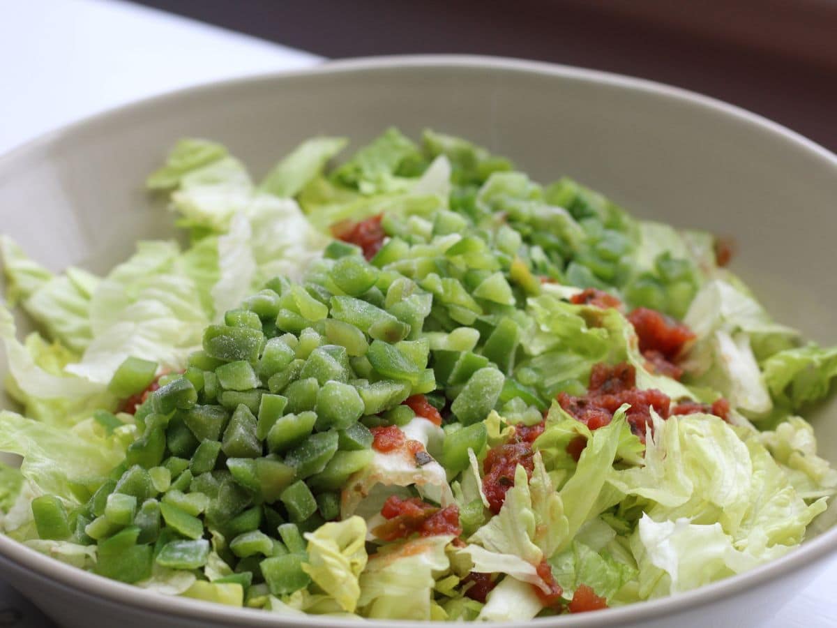 adding green peppers to salad