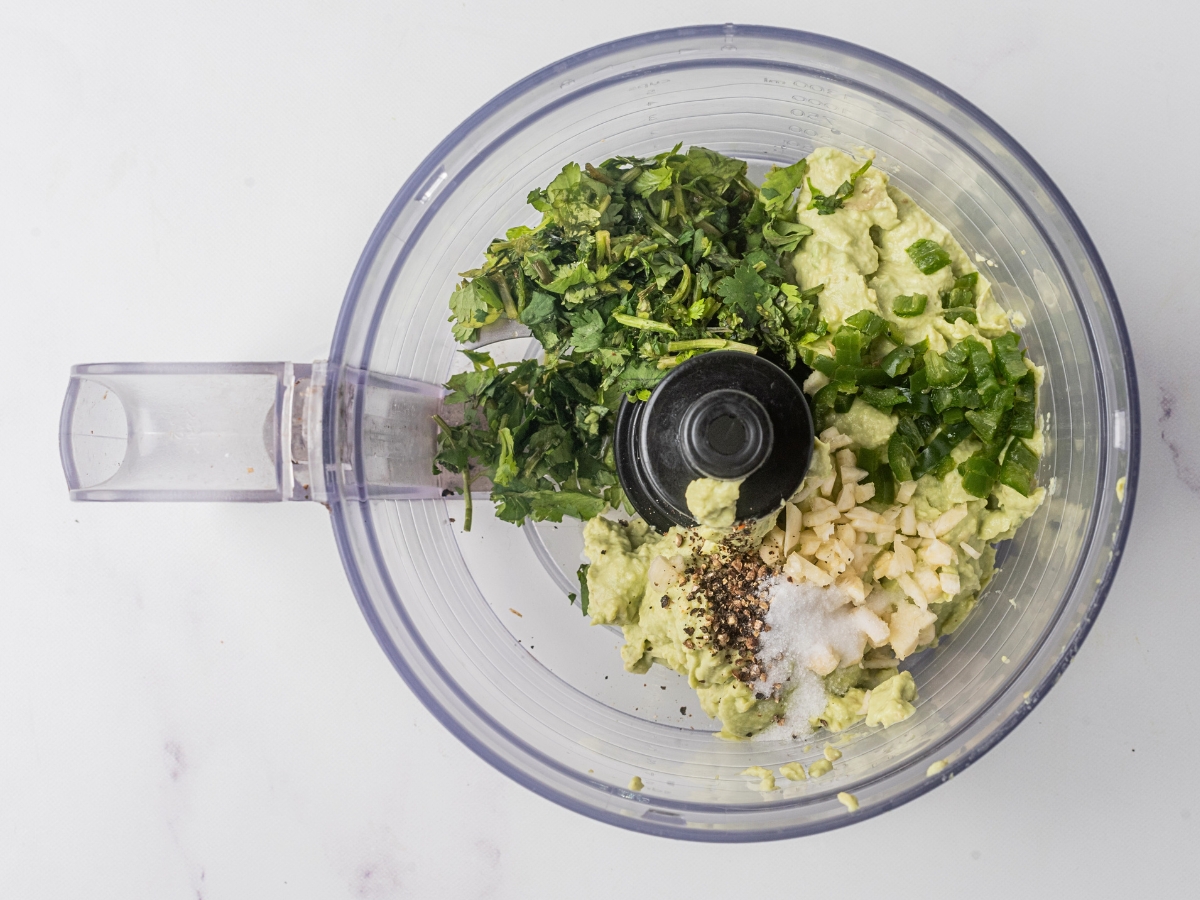 adding herbs and garlic to food processor