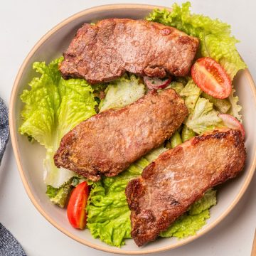 boneless pork ribs on top of a lettuce and tomatoes