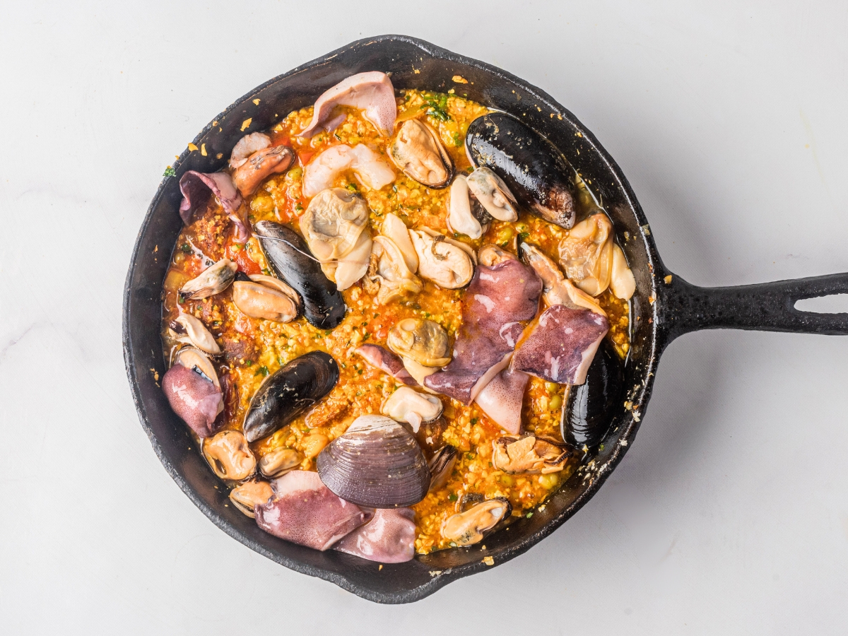 adding raw seafood in cast iron skillet