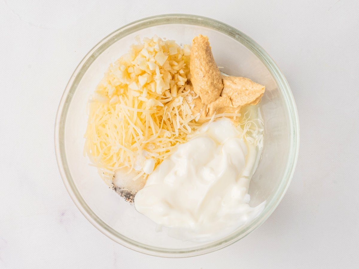 all ingredients for caesar dressing in a glass bowl