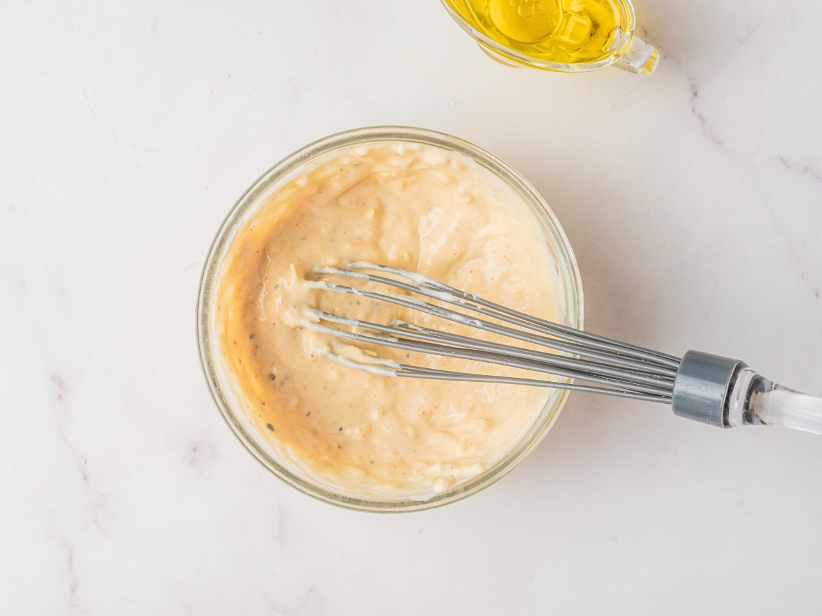 whisking homemade caesar dressing in a bowl